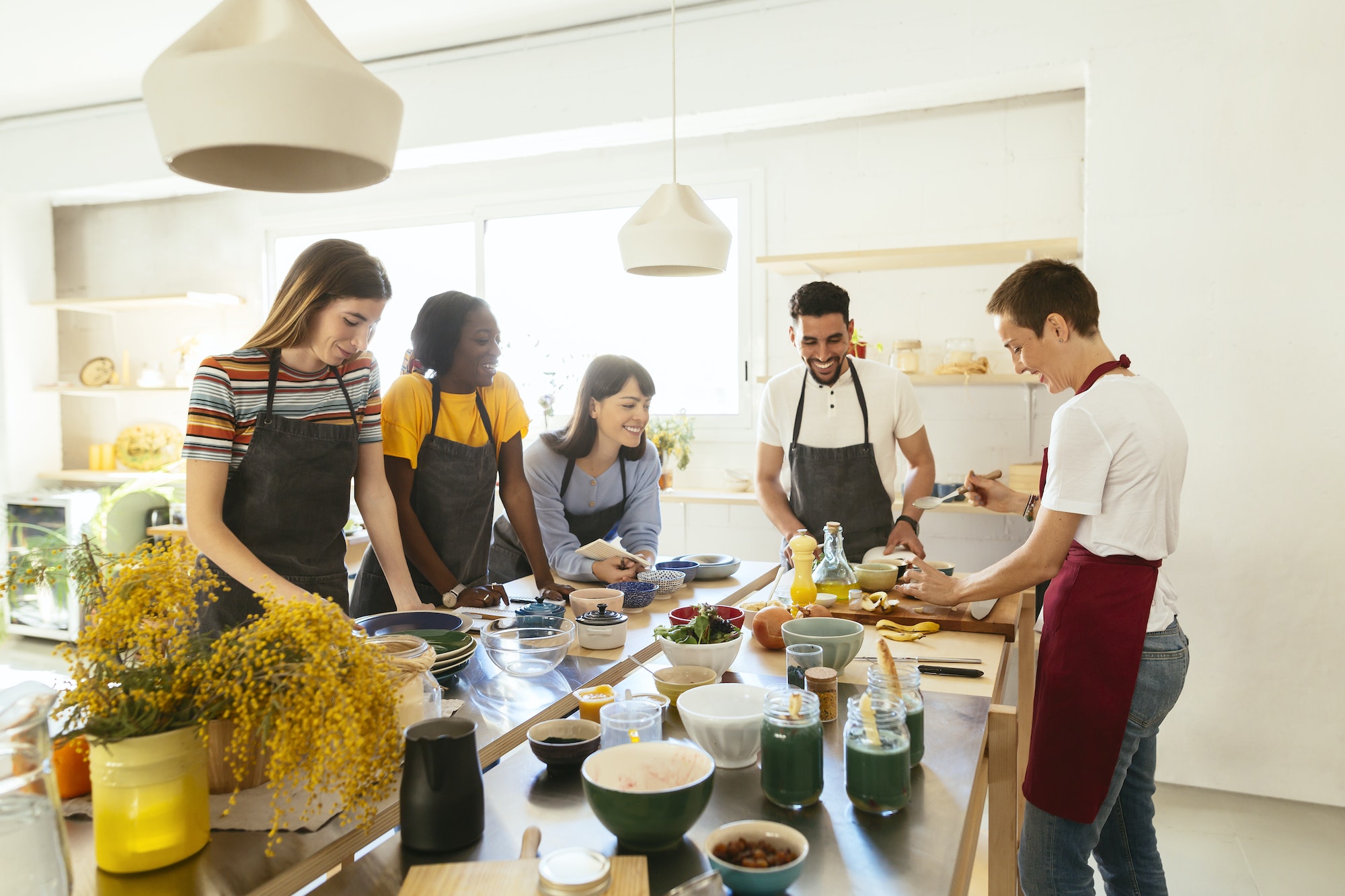 Friends and instructor in a cooking workshop preparing food